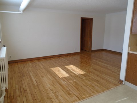 an empty living room with wooden floors and a door